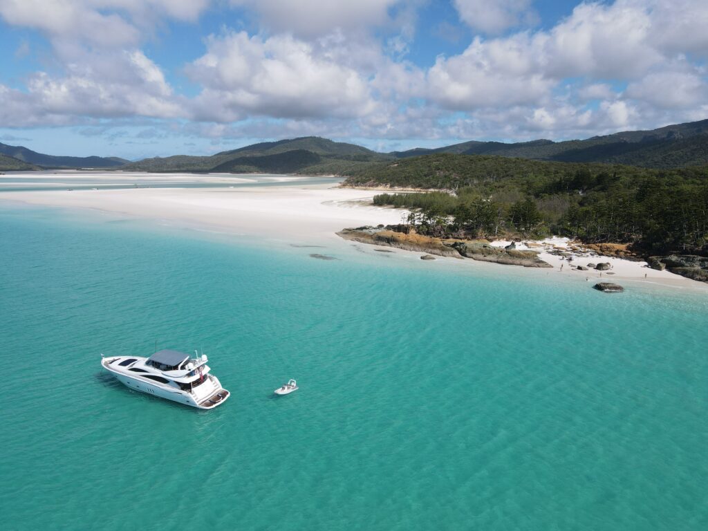 Aerial view of M/Y ALANI anchored off a long white-sand beach in the Whitsundays